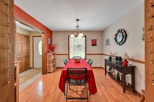 dining room featuring light hardwood / wood-style flooring, a textured ceiling, and a notable chandelier