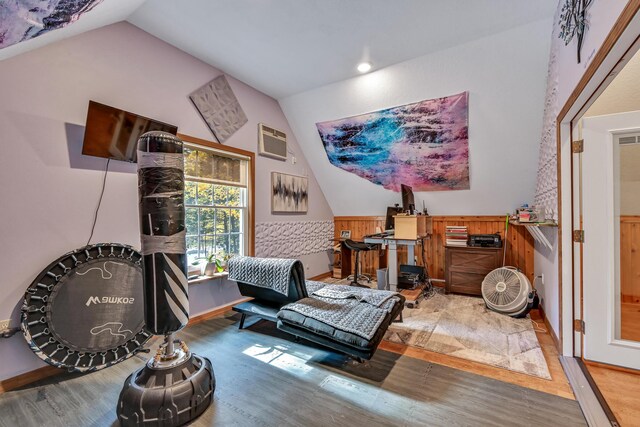 living area with hardwood / wood-style flooring, a wall mounted air conditioner, wooden walls, and vaulted ceiling