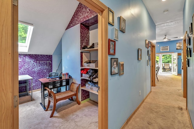 corridor featuring light colored carpet, lofted ceiling with skylight, and a textured ceiling