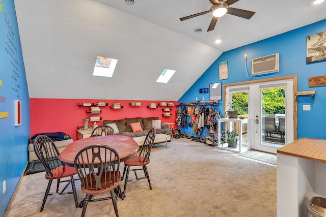 dining area featuring a wall mounted air conditioner, light carpet, french doors, vaulted ceiling with skylight, and ceiling fan