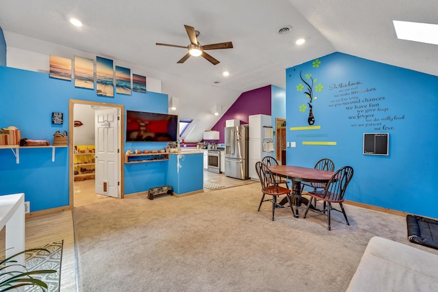 carpeted dining space featuring ceiling fan and vaulted ceiling with skylight