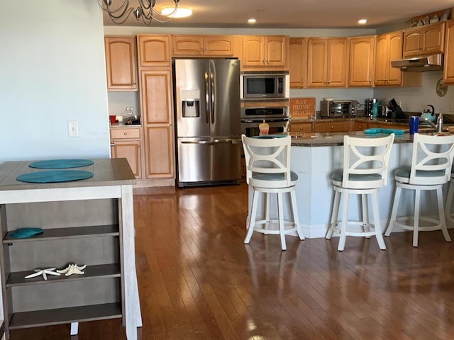 kitchen with a breakfast bar, a kitchen island, dark hardwood / wood-style floors, and appliances with stainless steel finishes