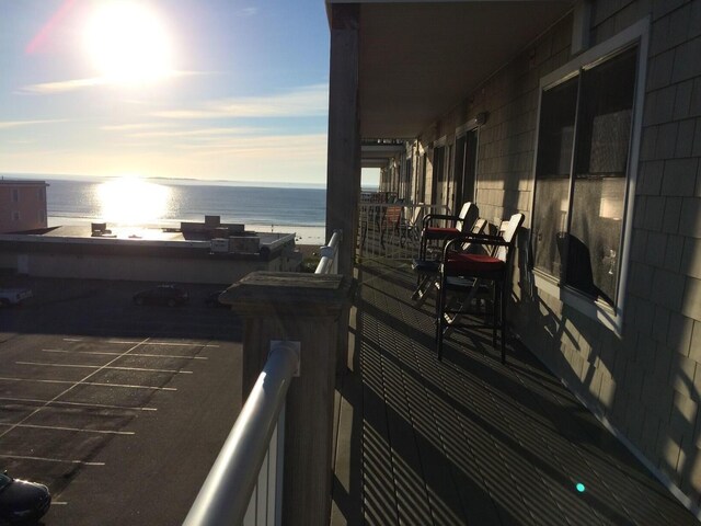 balcony at dusk featuring a water view