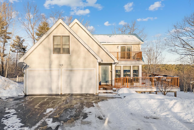 snow covered rear of property featuring a balcony and a garage