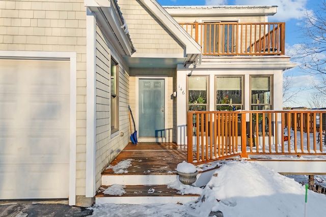 snow covered property entrance featuring a balcony and a garage