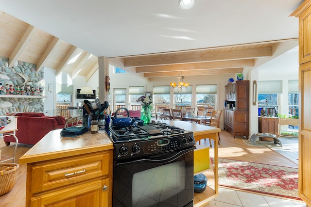 kitchen with hanging light fixtures, a stone fireplace, black gas stove, a chandelier, and light tile patterned floors