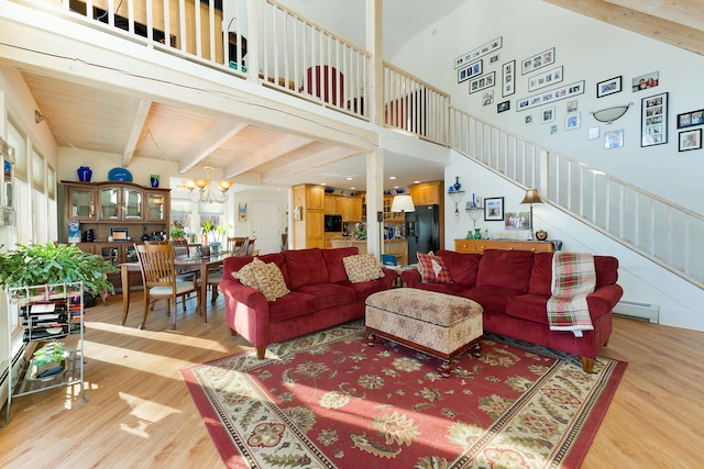 living room with beamed ceiling, a towering ceiling, hardwood / wood-style floors, and a baseboard heating unit