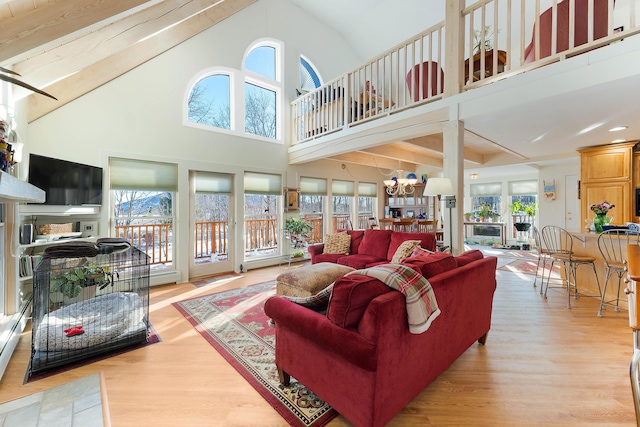 living room with a healthy amount of sunlight, light wood-type flooring, a high ceiling, and a chandelier