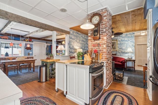 kitchen with wood counters, stainless steel range with electric cooktop, white cabinets, hanging light fixtures, and light hardwood / wood-style floors