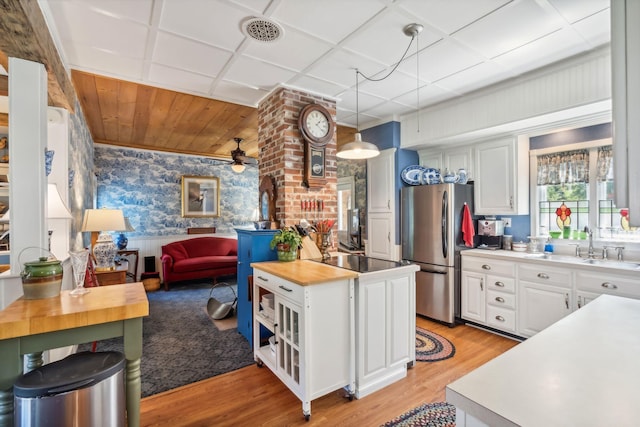 kitchen with pendant lighting, white cabinets, ceiling fan, light wood-type flooring, and stainless steel refrigerator