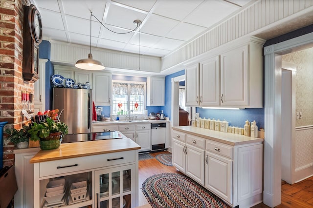 kitchen with stainless steel fridge, light wood-type flooring, white cabinetry, and hanging light fixtures