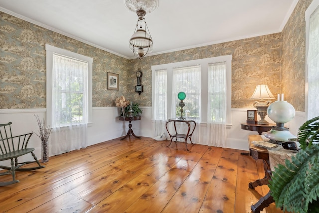 sitting room with a healthy amount of sunlight, wood-type flooring, and crown molding