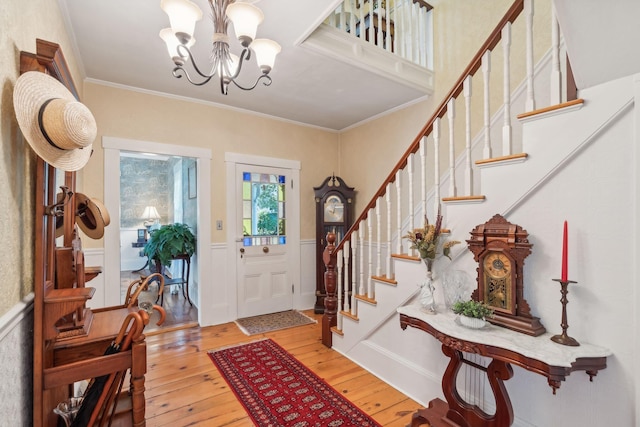 entryway featuring light hardwood / wood-style floors, crown molding, and an inviting chandelier