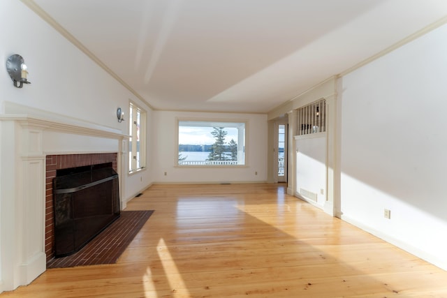 unfurnished living room with ornamental molding, light hardwood / wood-style floors, and a brick fireplace