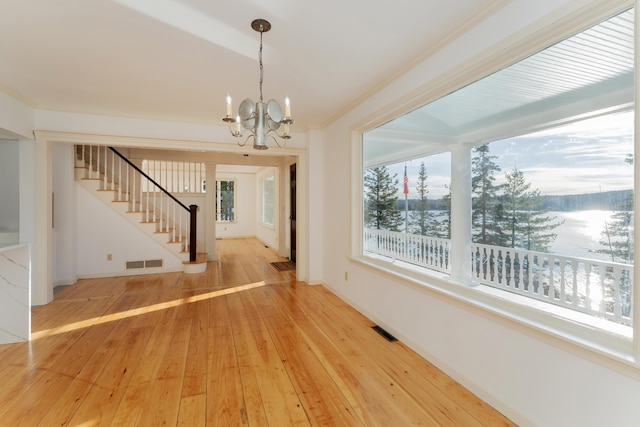 interior space featuring hardwood / wood-style flooring, crown molding, and an inviting chandelier