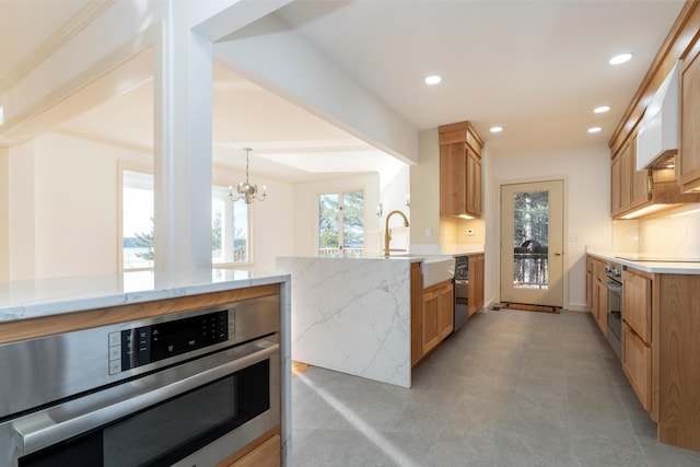 kitchen featuring sink, light stone counters, pendant lighting, a chandelier, and black appliances