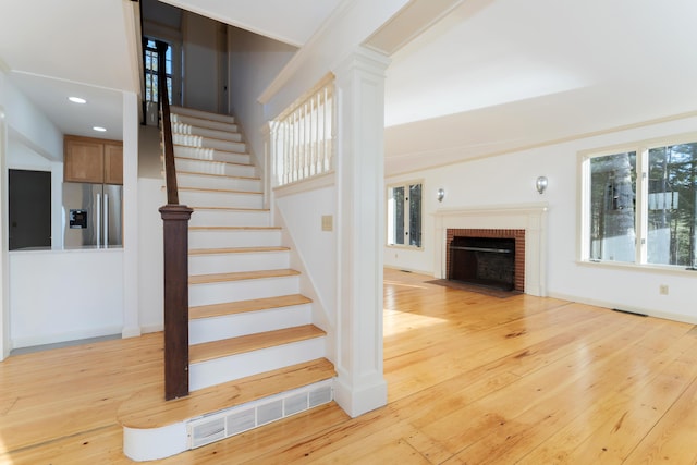 stairway featuring crown molding, wood-type flooring, and a brick fireplace