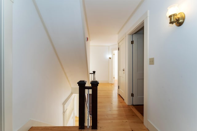 hall with light hardwood / wood-style floors and crown molding