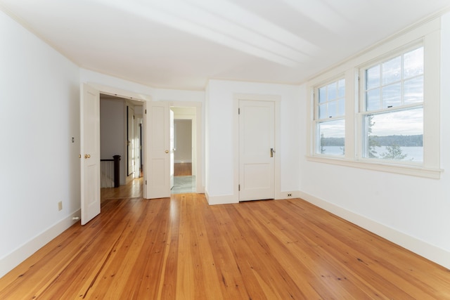 spare room featuring a wealth of natural light, ornamental molding, and light wood-type flooring