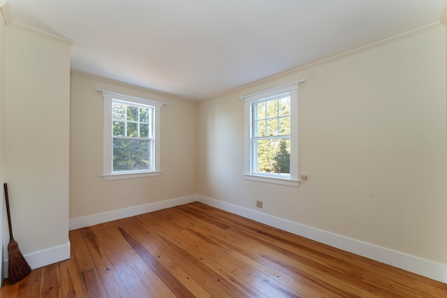 spare room with hardwood / wood-style flooring, plenty of natural light, and crown molding