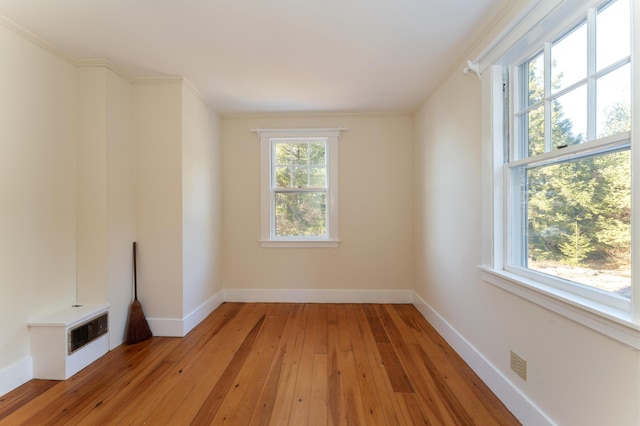 spare room with ornamental molding, a healthy amount of sunlight, and light wood-type flooring