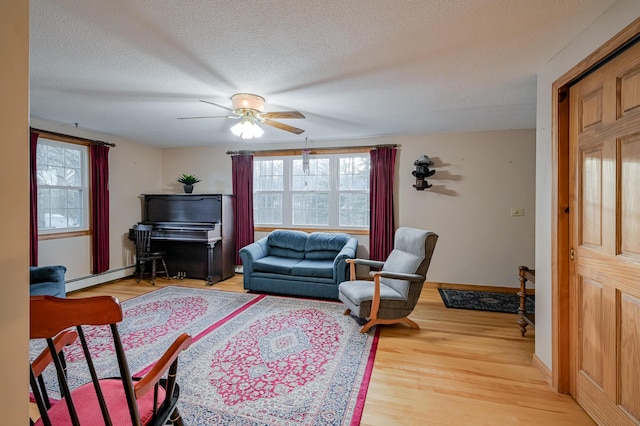 living room with a textured ceiling, hardwood / wood-style flooring, ceiling fan, and a baseboard heating unit