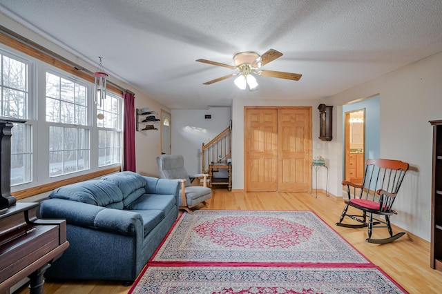 living room with hardwood / wood-style flooring, ceiling fan, and a textured ceiling