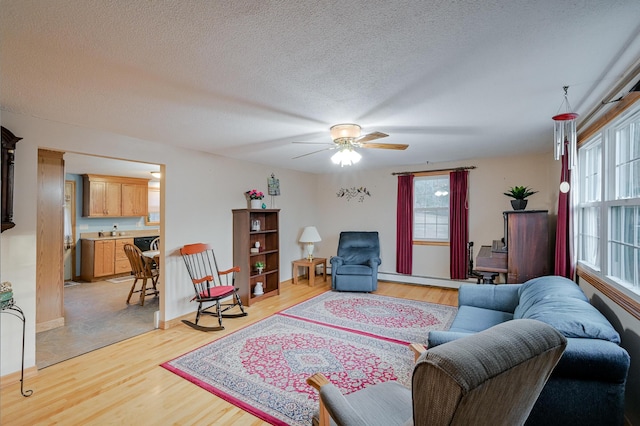 living room with a textured ceiling, light hardwood / wood-style flooring, and ceiling fan