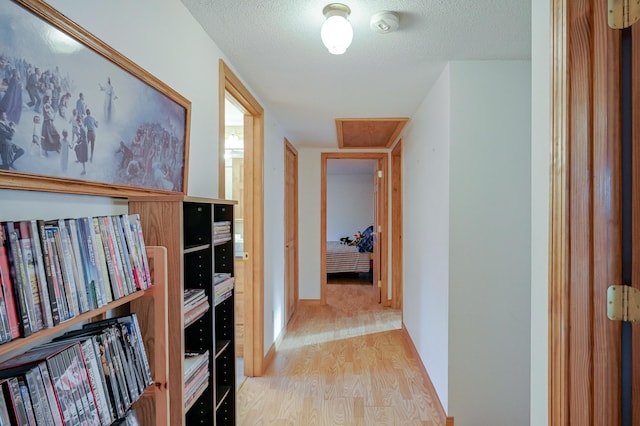 hallway with light wood-type flooring and a textured ceiling