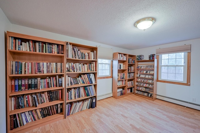 sitting room with light hardwood / wood-style floors, a healthy amount of sunlight, a textured ceiling, and a baseboard heating unit