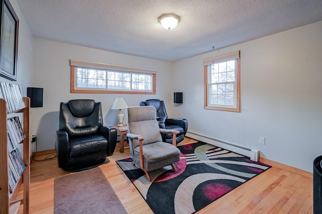 living area with baseboard heating, a wealth of natural light, and light hardwood / wood-style floors