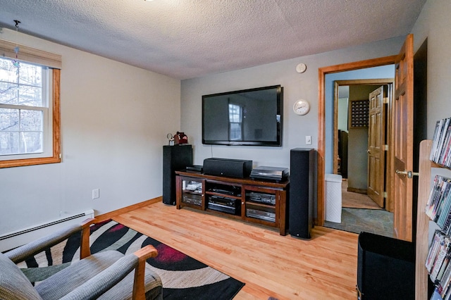 living room with hardwood / wood-style floors, baseboard heating, and a textured ceiling