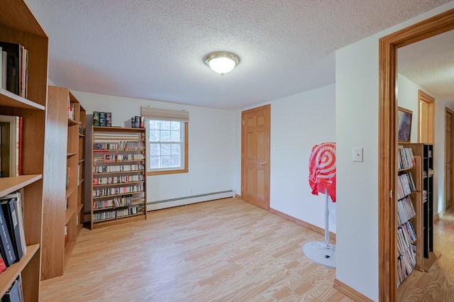 interior space with a baseboard radiator, light hardwood / wood-style floors, and a textured ceiling