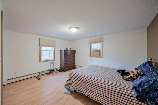 bedroom with cooling unit, wood-type flooring, a textured ceiling, and a baseboard heating unit