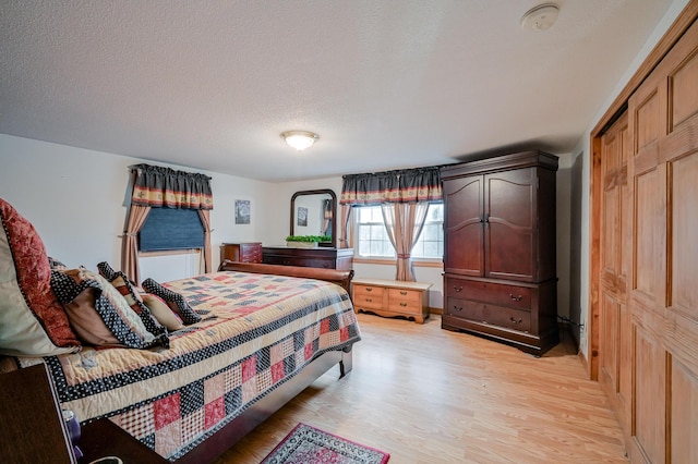 bedroom featuring a textured ceiling, light hardwood / wood-style floors, and a closet