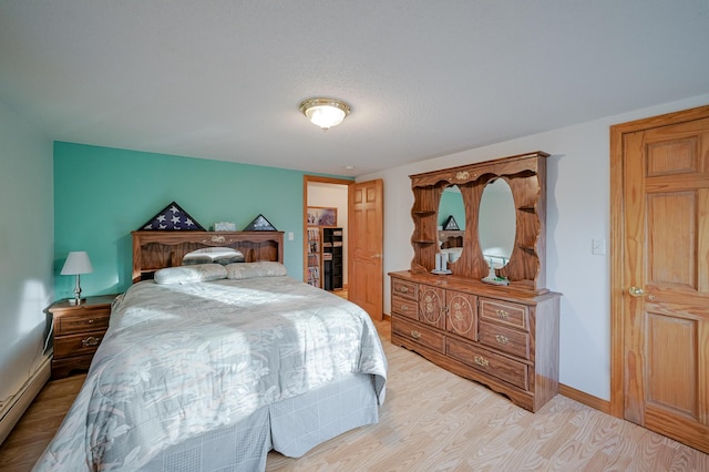 bedroom with light hardwood / wood-style flooring and a baseboard radiator