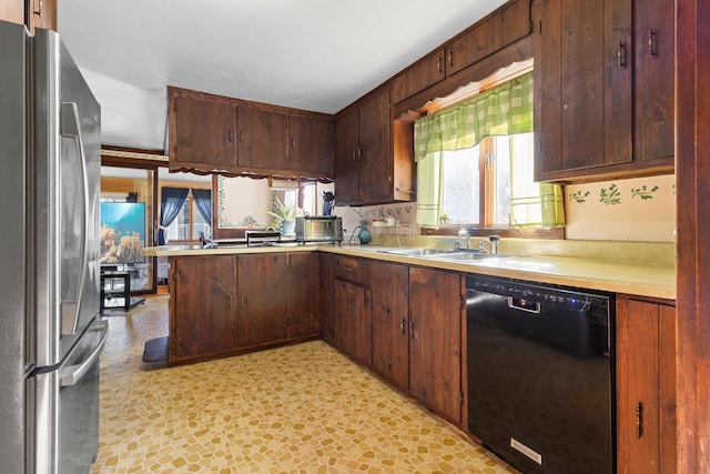 kitchen with kitchen peninsula, black dishwasher, stainless steel refrigerator, and sink