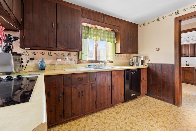 kitchen featuring wooden walls, dishwasher, stovetop, and sink