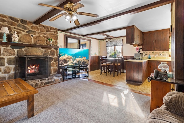 living room with beamed ceiling, ceiling fan, a fireplace, and light carpet