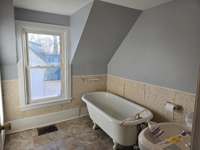 bathroom with a bathing tub and tile walls