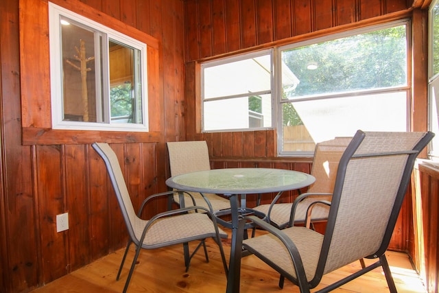 dining space featuring light wood-type flooring, a wealth of natural light, and wood walls