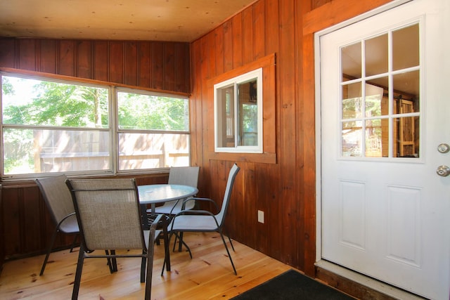 dining room with light wood-type flooring and wood walls