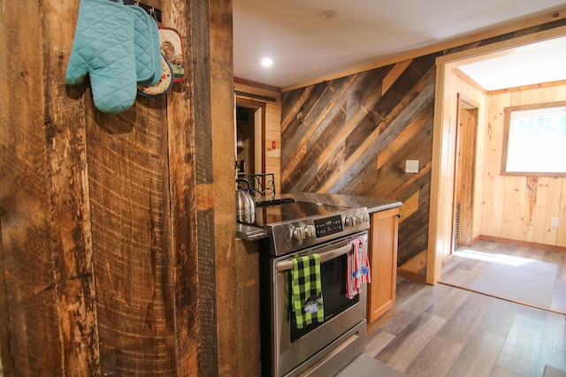 kitchen featuring hardwood / wood-style floors, stainless steel range with electric cooktop, and wooden walls