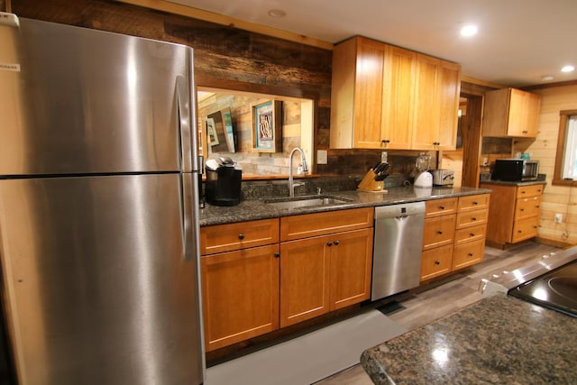 kitchen featuring appliances with stainless steel finishes, tasteful backsplash, dark stone counters, and sink