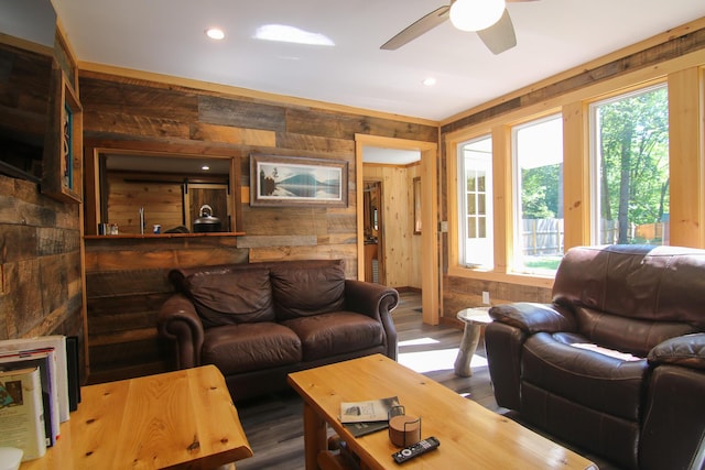 living room with dark hardwood / wood-style floors, ceiling fan, and wood walls