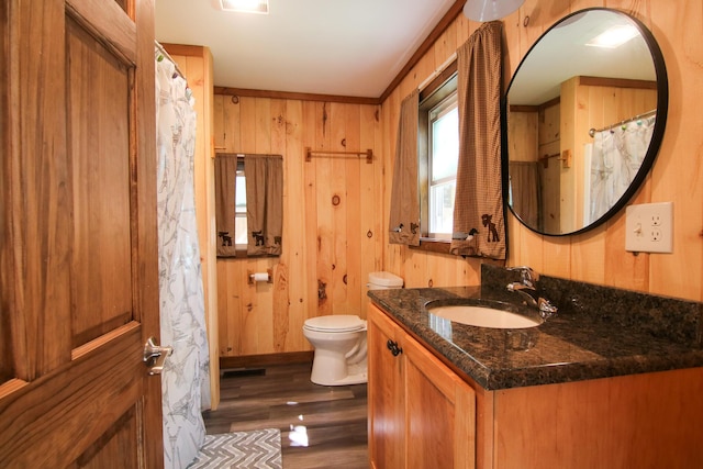 bathroom featuring wood walls, toilet, hardwood / wood-style flooring, vanity, and ornamental molding