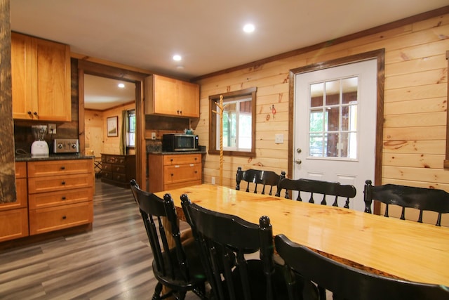 dining space with dark wood-type flooring and wooden walls