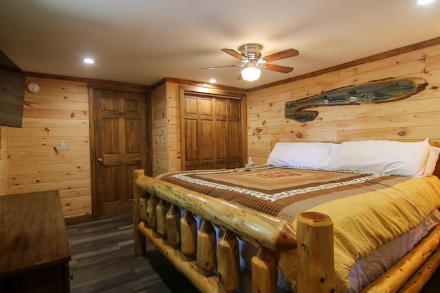 bedroom featuring ceiling fan, wood walls, dark wood-type flooring, and a closet