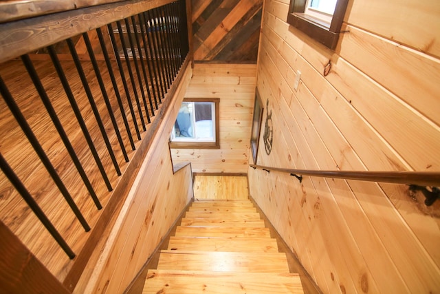 stairs featuring hardwood / wood-style floors and wood walls