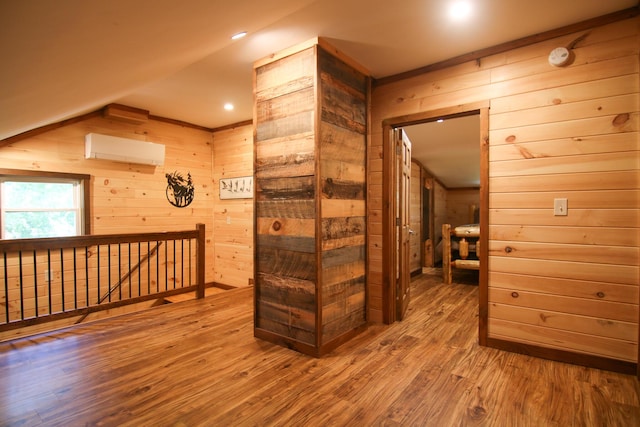 hallway with a wall mounted air conditioner, hardwood / wood-style floors, and wooden walls